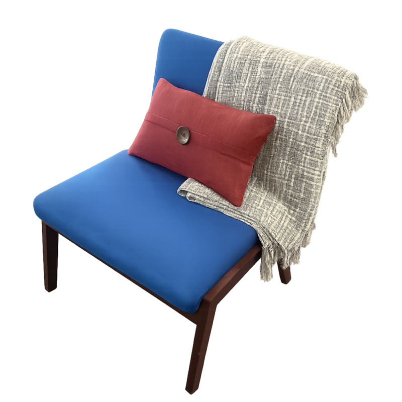 Blue upholstered lounge chair with wooden legs, accented by a red lumbar pillow and a gray woven throw draped over the back as a cozy seating setup.