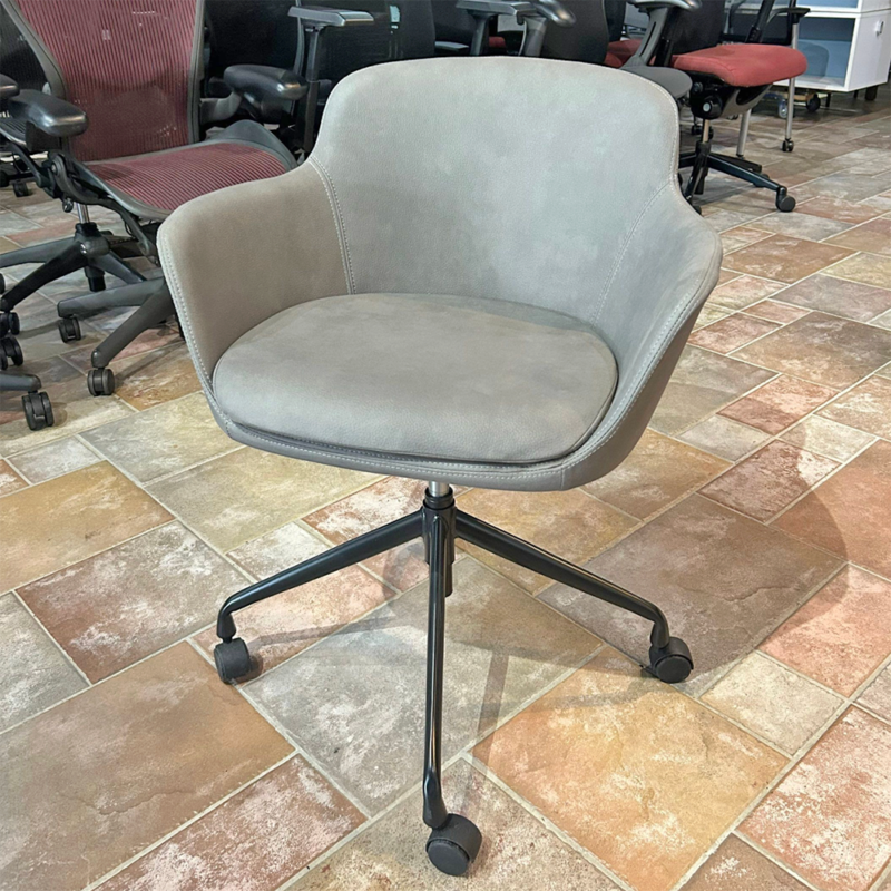 Gray upholstered swivel office chair with curved armrests and a five-wheel base on a tiled showroom floor.