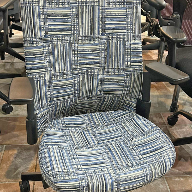 Blue patterned office chair with padded back and seat on a five-star base with casters in a showroom.