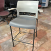 White modern bar stool with a backrest and gray cushioned seat in a showroom on tile flooring.
